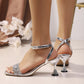 Sandalen mit Knöchelriemen und Strasssteinen sowie skulpturalem Absatz